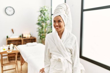 Güzellik merkezinde bornoz giyen genç Latin kadın.