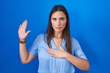 Mavi arka planda duran genç esmer kadın, el pençe divan durup, sadakat yemini ediyor. 