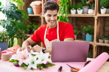 Çiçekçide dizüstü bilgisayar kullanan İspanyol bir çiçekçi.