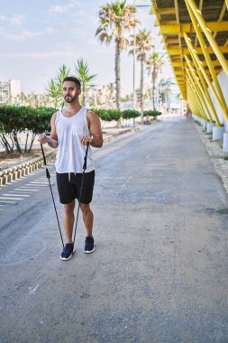 Güneşli bir günde esnek bantlarla çalışan İspanyol bir adam.