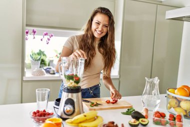 Genç, güzel İspanyol kadın mutfakta sebze suyu ve blender hazırlıyor.