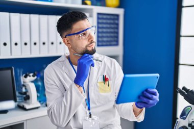 Genç Arap bilim adamı laboratuarda çalışan dokunmatik ped kullanıyor.