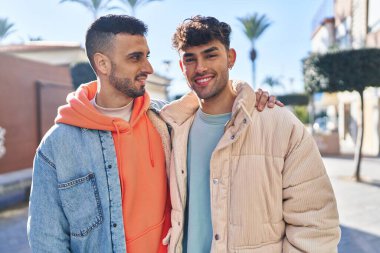 İki erkek caddede birbirlerine sarılıyorlar.