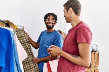 İki erkek arkadaş giyim mağazasında akıllı telefon kullanarak kıyafet seçiyor.