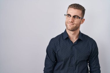 Young caucasian man standing over isolated background smiling looking to the side and staring away thinking. 