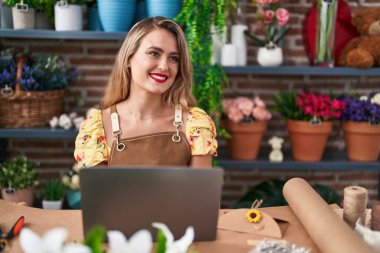 Young beautiful hispanic woman florist smiling confident using laptop at flower shop