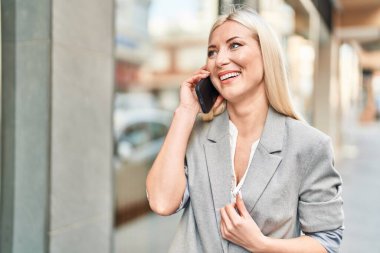 Sokakta akıllı telefon kullanan, kendine güvenen genç sarışın kadın.