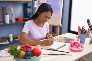 Sanat stüdyosunda kendine güvenen, gülümseyen Afrikalı Amerikalı kadın sanatçı.