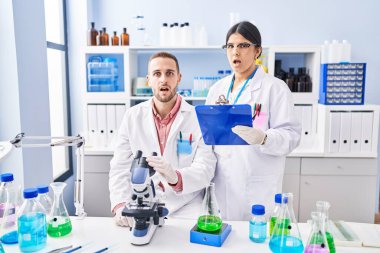 Laboratuvarda çalışan iki genç insan korku ve şaşkınlık içinde ağzı açık bir şekilde şaşkınlık içinde, inançsız bir yüz ifadesi takınıyorlar. 