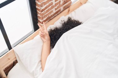 Orta Doğulu genç bir kadın yatak odasında parmaklarıyla zafer jesti yapıyor.