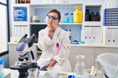 Down sendromlu İspanyol kız bilim adamı laboratuarında çalışıyor şüphe üzerine kafa yoruyor çenesi parmaklarıyla yukarı bakıyor ve merak ediyor 