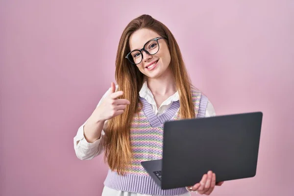 年轻的高加索女人在工作时 用电脑笔记本电脑 手指着相机 脸上带着快乐和滑稽的表情 充沛的精力和活力 — 图库照片