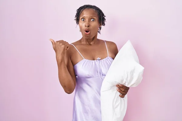 African Woman Dreadlocks Wearing Pajama Hugging Pillow Surprised Pointing Hand — 图库照片