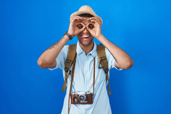 ビンテージカメラを持っているブラジルの若い男は 双眼鏡が舌を突き出しているようなOkジェスチャーをして 目は指を見ている クレイジーな表現 — ストック写真