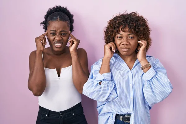Two African Women Standing Pink Background Covering Ears Fingers Annoyed — Stok fotoğraf