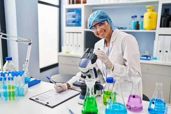 Νεαρή Λατίνα Γυναίκα Που Φοράει Στολή Επιστήμονα Χρησιμοποιώντας Μικροσκόπιο Στο — Φωτογραφία Αρχείου