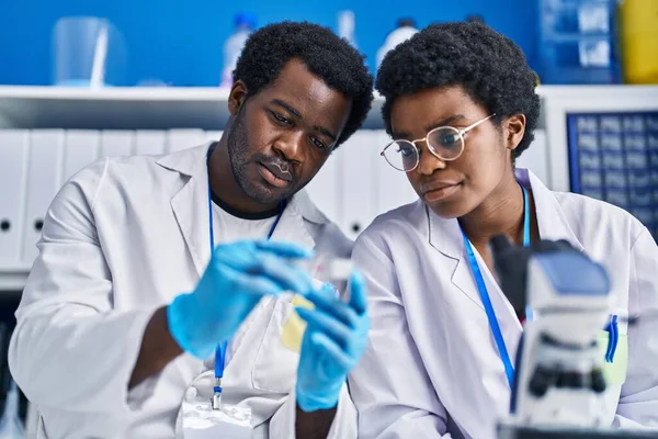 アフリカ系アメリカ人の男性と女性科学者が実験室でサンプルを持ち — ストック写真