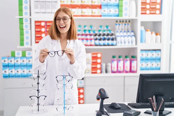 Young Redhead Woman Working Pharmacy Drugstore Holding Glasses Smiling Laughing — Foto de Stock