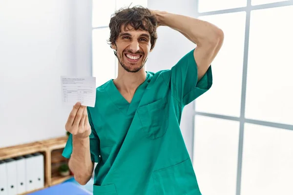 Young Hispanic Doctor Man Holding Covid Record Card Smiling Confident — Stockfoto