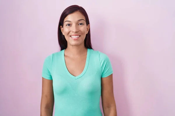 幸せとクールな笑顔でピンクの背景の上に立って若いヒスパニック系の女性 運のいい人 — ストック写真