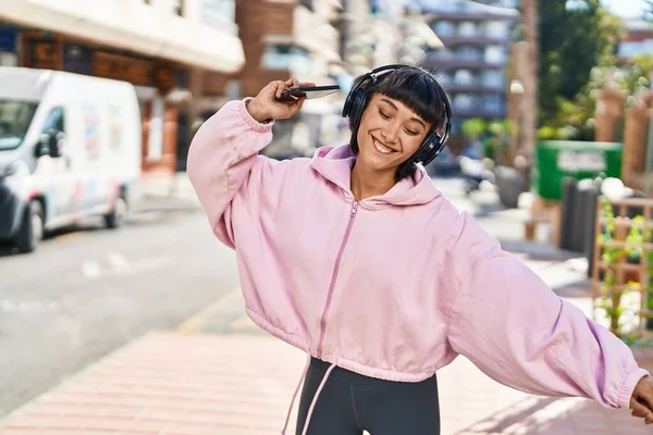 Young woman listening to music and dancing at street