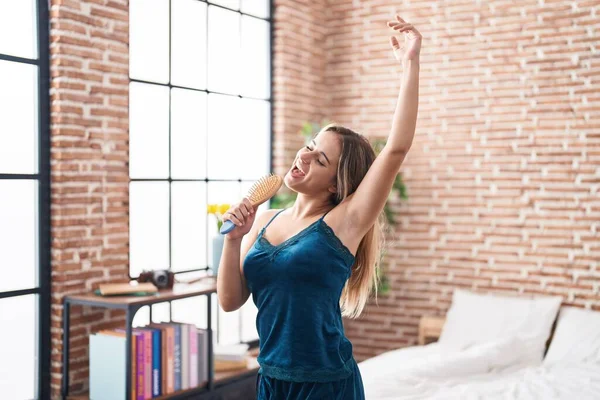 Young Blonde Woman Singing Song Using Brush Microphone Bedroom — Stock Photo, Image