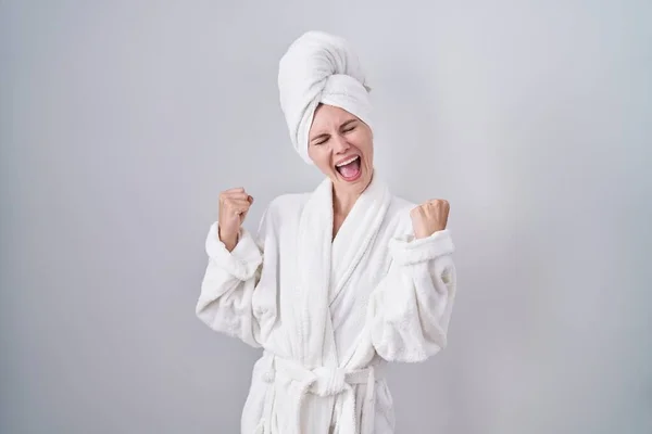 金发女人穿着浴衣 高兴而兴奋地举起双臂 做着获胜的手势 微笑着 尖叫着要成功 庆祝概念 — 图库照片