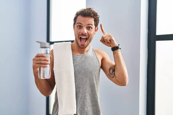 Jonge Spaanse Man Draagt Sportkleding Drinkwater Glimlachend Verbaasd Verrast Wijzend — Stockfoto