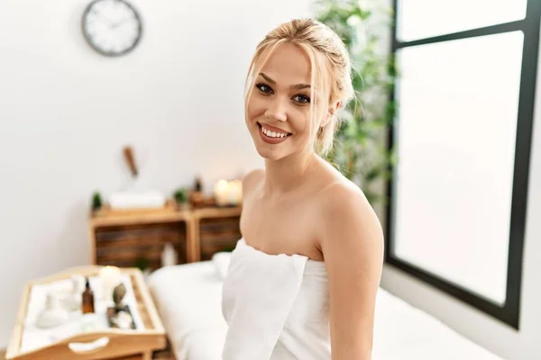 stock image Young caucasian woman wearing towel sitting on massage board at beauty salon