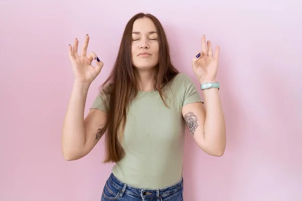 站在粉色背景上的美丽的黑发女人放松了 闭上了眼睛 用手指做冥想动作 瑜伽概念 — 图库照片