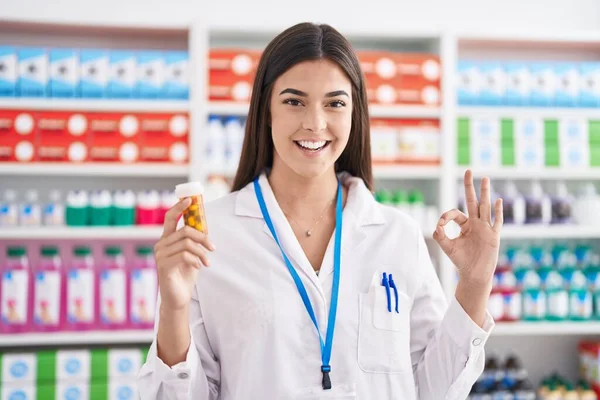 Mulher Hispânica Trabalhando Farmácia Farmácia Segurando Pílulas Fazendo Sinal Com — Fotografia de Stock