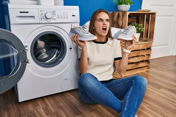 Young Woman Putting Sneakers Washing Machine Angry Mad Screaming Frustrated — Φωτογραφία Αρχείου