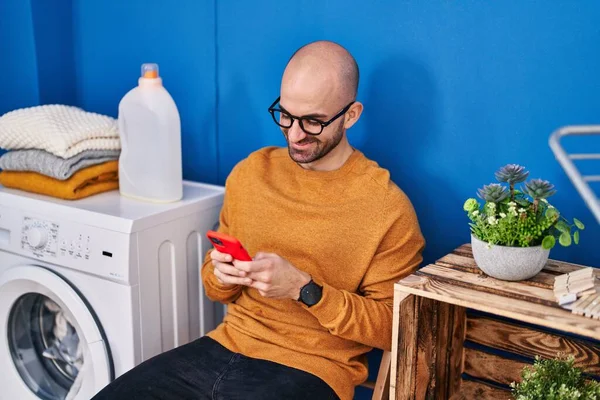 Ung Man Med Smartphone Väntar Tvättmaskin Tvättstugan — Stockfoto