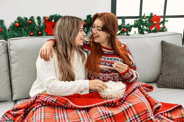 stock image Woman couple hugging each other watching tv sitting by christmas decor at home