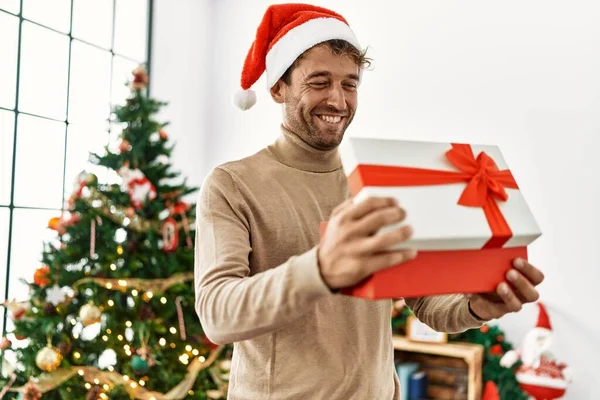 Joven Hombre Hispano Sonriendo Confiado Sosteniendo Regalo Navidad Casa —  Fotos de Stock