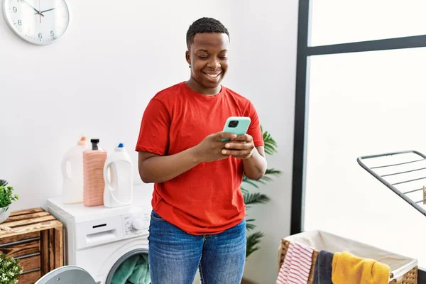 Young African Man Using Smartphone Laundry Room — ストック写真