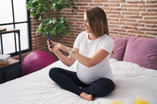 Jonge Zwangere Vrouw Met Smartphone Aanraken Buik Slaapkamer — Stockfoto