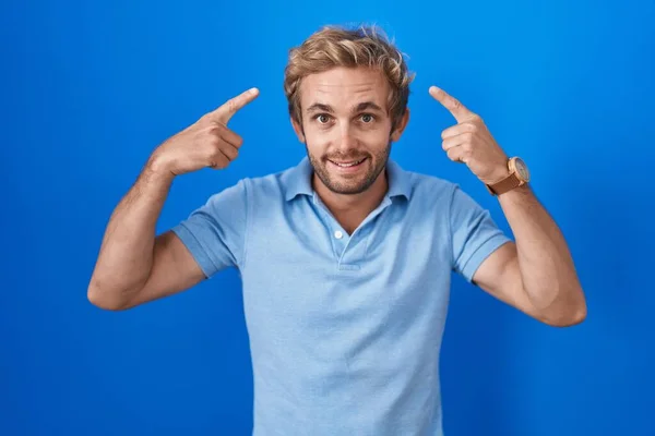 Caucasian Man Standing Blue Background Smiling Pointing Head Both Hands — Foto Stock