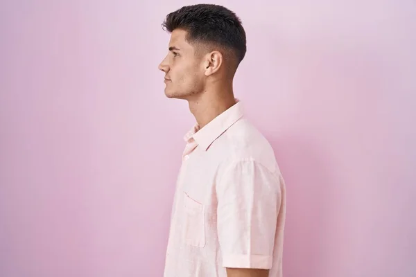 Νεαρός Ισπανόφωνος Στέκεται Πάνω Από Ροζ Φόντο Κοιτάζοντας Προς Πλάγια — Φωτογραφία Αρχείου