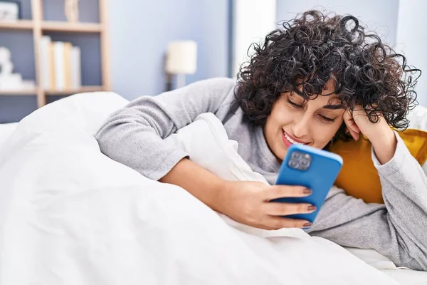Νεαρή Γυναίκα Της Μέσης Ανατολής Χρησιμοποιώντας Smartphone Ξαπλωμένη Στο Κρεβάτι — Φωτογραφία Αρχείου