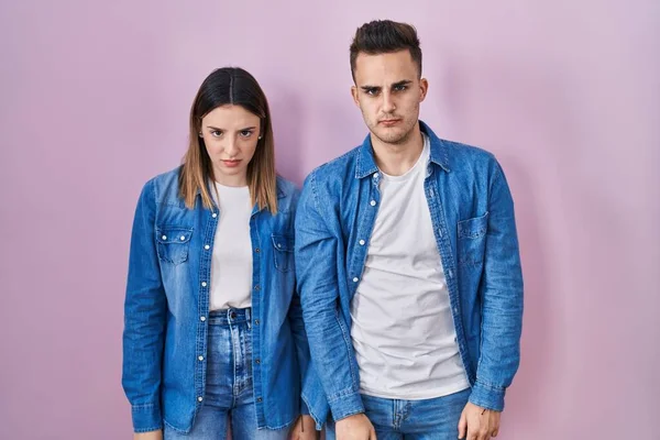 Young Hispanic Couple Standing Pink Background Skeptic Nervous Frowning Upset — Stockfoto