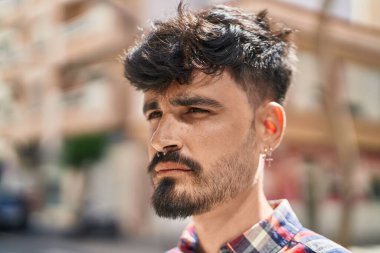 Young hispanic man looking to the side with relaxed expression at street