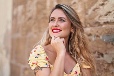 Young beautiful hispanic woman smiling confident looking to the side over isolated stone background