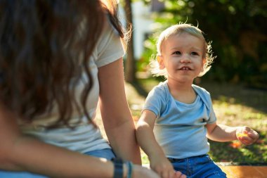Anne ve oğlu bankta oturup parkta küçük solucanlar yiyorlar.