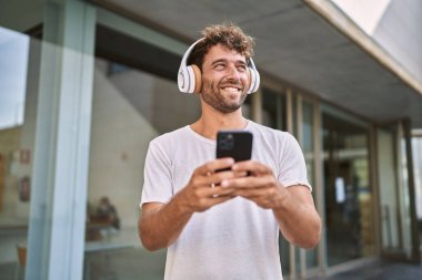 Sokakta müzik dinlerken kendinden emin gülümseyen İspanyol genç adam.