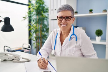 Middle age woman wearing doctor uniform working at clinic