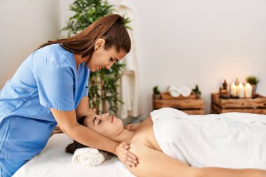 İki kadın terapist ve hasta güzellik merkezinde yüz masajı yapıyorlar.