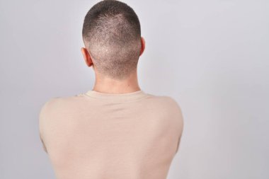 İzole edilmiş arka planda duran genç adam geriye doğru çapraz kollarla bakıyor. 