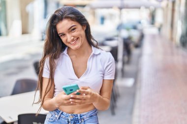 Sokakta akıllı telefon kullanan, kendine güvenen genç İspanyol kadın.