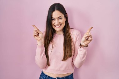 Pembe arka planda duran esmer kadın farklı yönleri gösteren kendine güvenen bir şekilde gülümsüyor. reklam için kopyalama alanı 